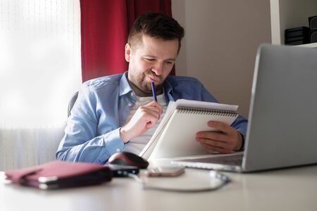 Young caucasian man working from home reading documents