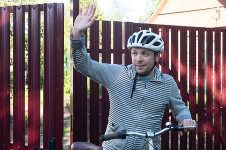 Man in helmet with a bike waving hand welcoming his hand.の写真素材
