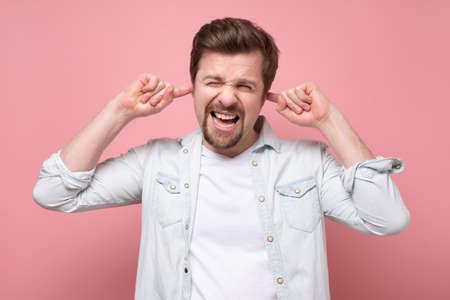 Man with closed ears. Guy does not like a loud noise from neighbors.の写真素材