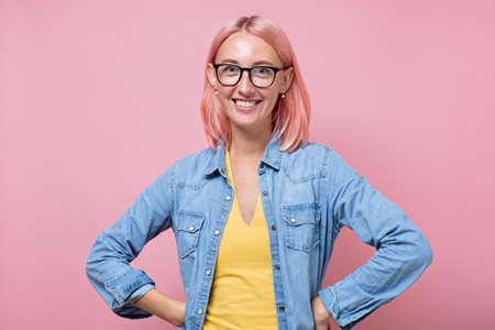 Gorgeous young woman with dyed pink hair with charming smile looking at camera.