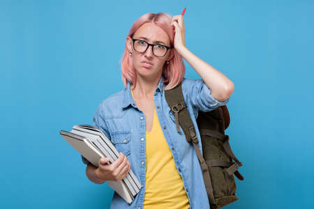 puzzled student with books scratching her head trying to make a decision.