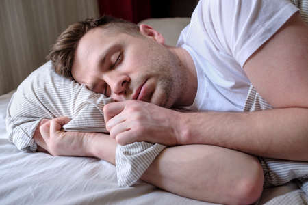 Young man sleeping in bed, at home.の写真素材