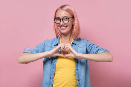 Woman in glasses gesturing heart shape with handsの写真素材