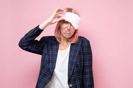 Caucasian woman peeping from a sleeping mask, feeling tired.の写真素材