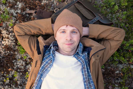 Man lies on the grass, resting in the middle of the forest relaxing