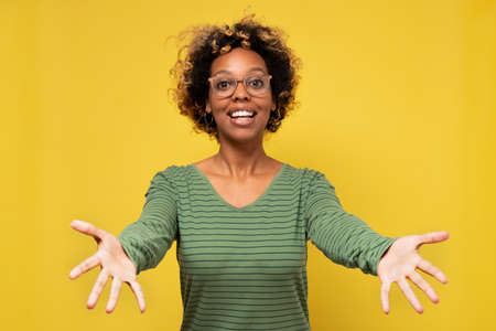 Young african american woman smiling with open arms for hug welcoming her friendsの写真素材