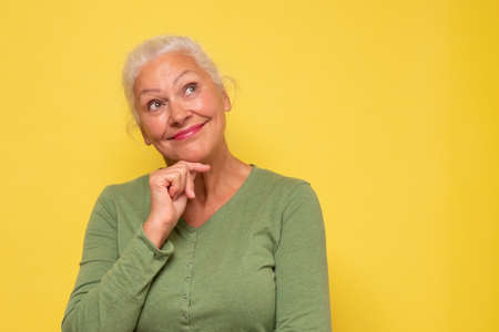 Beautiful senior hispanic woman looking up and thinkingの写真素材