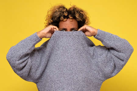 Displeased young afraid woman wearing a high neck sweater, hiding form problems.の写真素材