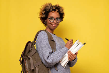 African american woman with backpack ready to study, writing some notes.の写真素材
