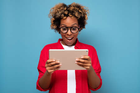Young african curly woman shocked by news displayed on a digital tablet.