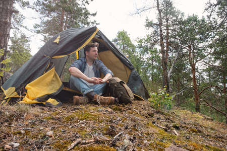 Mature caucasian man sitting in camping near tent after walking