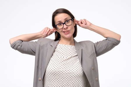 Caucasian young woman making funny monkey grimace pulling her ears