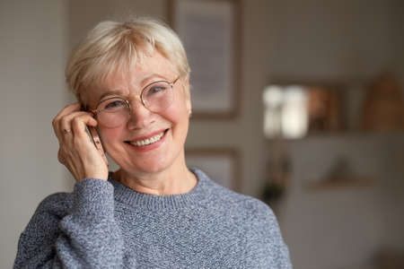 Senior woman smiling talking on phone at homeの写真素材