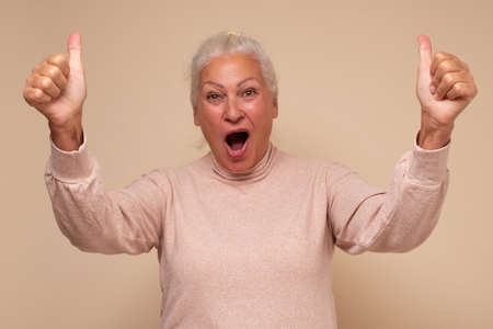 Happy senior woman showing her two thumbs up being happy making a choice
