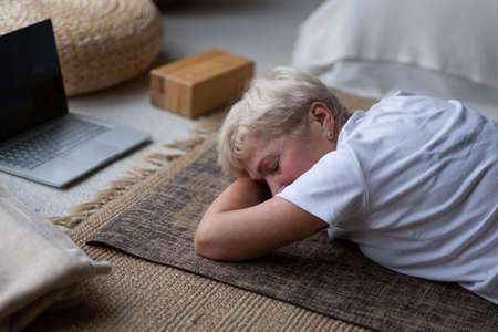 woman relaxes in yoga asana Makarasana or crocodile pose during online lesson