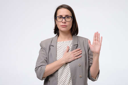 Woman swearing with hand on chest and open palm, making a loyalty promise oath.