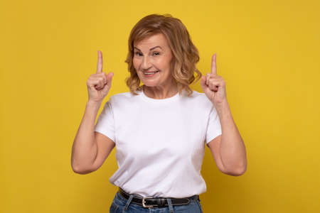 Senior smiling woman pointing up giving advice.の写真素材