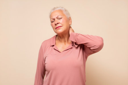 Senior hispanic woman holding her neck in pain and discomfortの写真素材