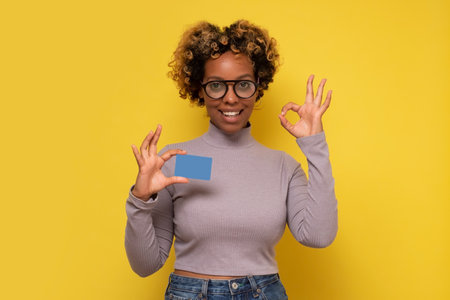 Smiling african american woman holding credit card and gesturing OK