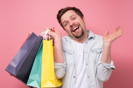 Happy caucasian young man with shopping bagsの写真素材