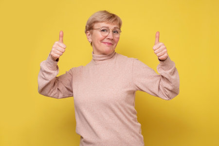 Middle age woman approving showing positive gesture with hand, thumbs upの写真素材