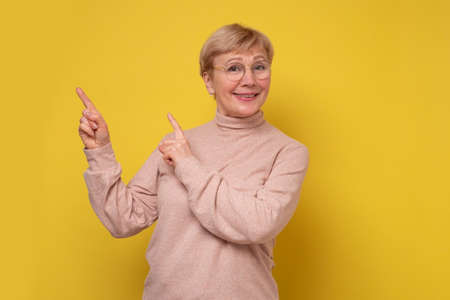 Happy mature lady looking at camera advertising product.