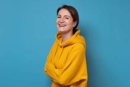 Laughing young casual woman with wide open mouth on blue backgroundの写真素材
