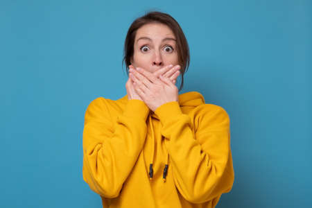Young caucasian woman covering with hand her mouth