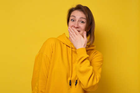 Young laughing woman covering her mouth being surprised with news.の写真素材