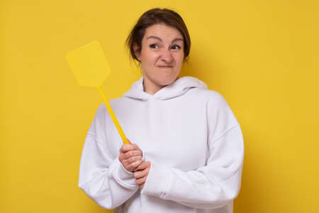 Angry caucasian woman with fly swatter looking for insects.の写真素材