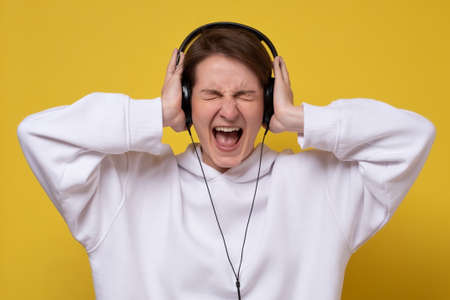 Young woman in headphones singing her favorite song screaming loudly.の写真素材