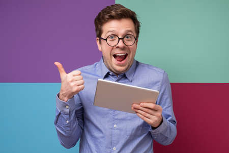 Caucasian mature businessman showing thumb up finding interesting information in internet.の写真素材