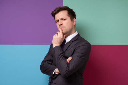 Young good looking suited man thinking trying to make a decision. Studio shot