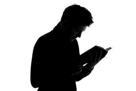 Silhouette of young man reading book. Student preparing for examの写真素材