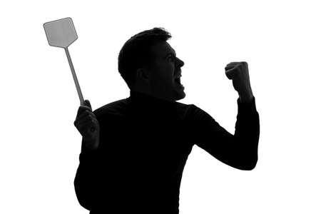 Silhouette of furious man trying to kill mosquito with fly swatter.の写真素材