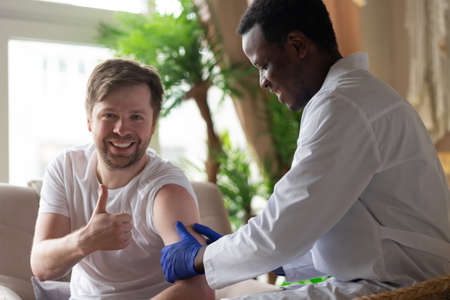 African doctor doing injection of vaccine to male patientの写真素材