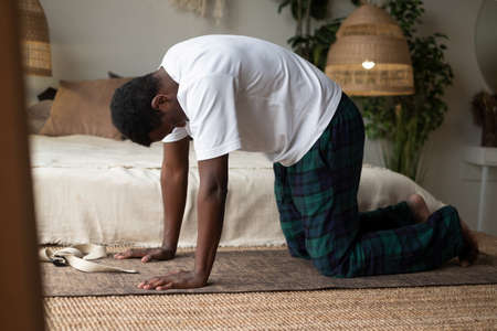 Sporty muscular young african man working out, yoga, pilates, fitness training, doing Cat Pose