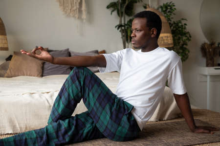 African mature man sitting in the twisted asana for spine