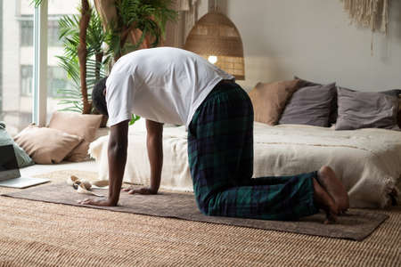 Sporty muscular young african man working out, yoga, pilates, fitness training, doing Cat Poseの写真素材