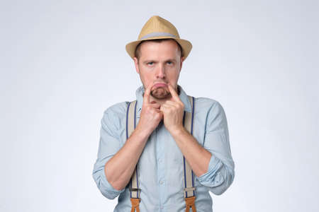 Worried caucasian man having bad mood showing sad smile.の写真素材