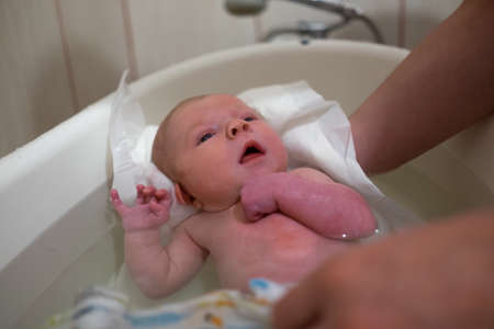 First bathing of a newborn baby girl at home.
