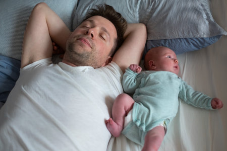 Young caucasian father and baby girl sleeping on bed together.