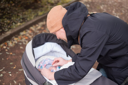 Happy young father with pram checking his baby during the walkの写真素材