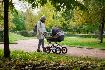 Happy young mother with pram during the walkの写真素材
