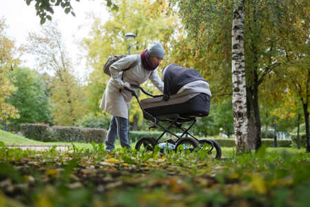 Happy young mother with pram during the walkの写真素材
