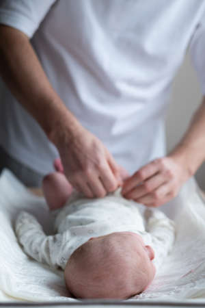 Caucasian father changing baby girl clean clothの写真素材