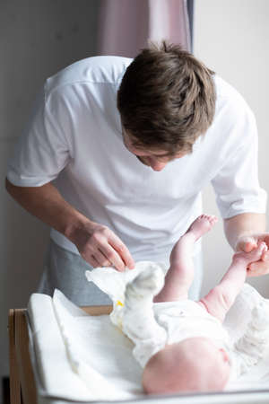 Father changing dirty stinky diaper with yellow poop for his newborn babyの写真素材