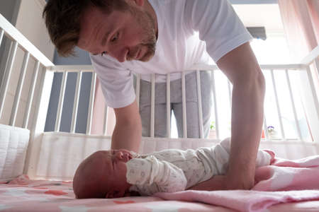 Young father trying to calm down his newborn baby holding her in his hands.の写真素材