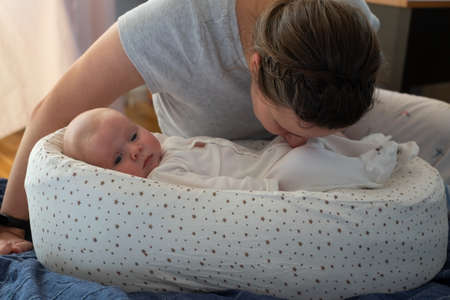 Mother sniffing stinky diaper of her little daughter checking if it is time to change it.