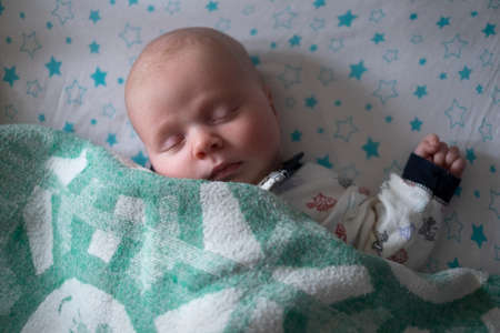Baby sleeping in bed with a blanket.